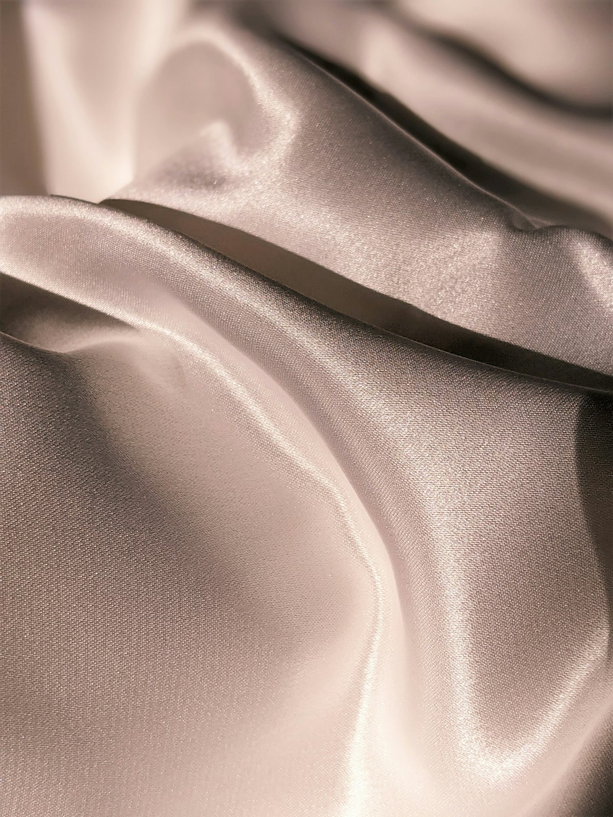 Silk fabric with a botanical sprig and brass dropper in warm editorial light